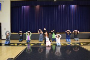 Amelia Lathem (Annie), Chloe Guzzetta (Molly) and the orphan company rehearse the popular song, "Hard Knock Life".