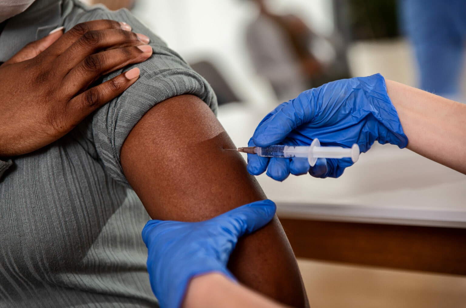 Close up of nurse hanks giving vaccine to patient in clinic.