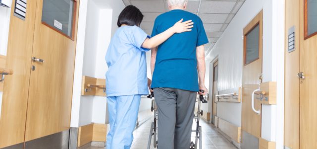 Asian nurse helping elder man walking in rehab facility